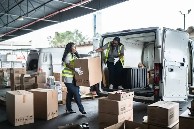 Last mile carrier team unloading delivery boxes from van at local warehouse