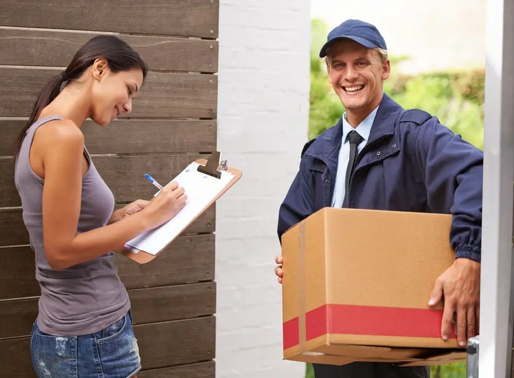 Courier delivering a package to a customer who is signing a proof of delivery form at the front door