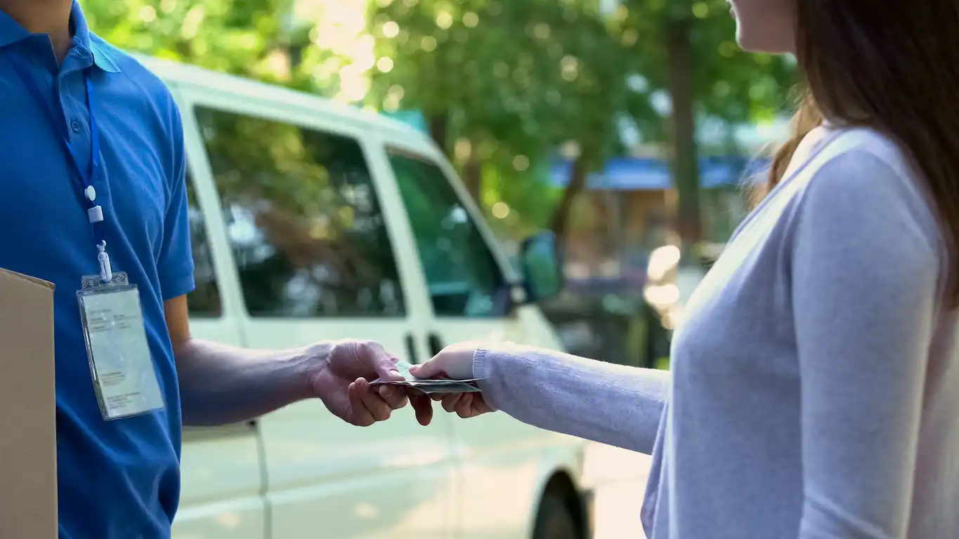 Customer handing cash to courier for delivery payment