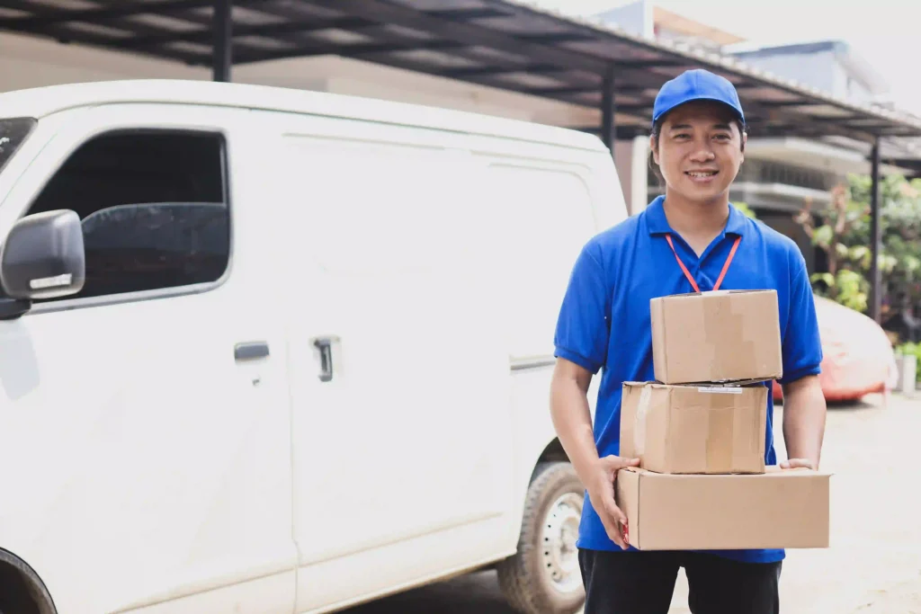 Difference between logistics and courier service shown by a courier delivery person holding packages in front of a delivery van.